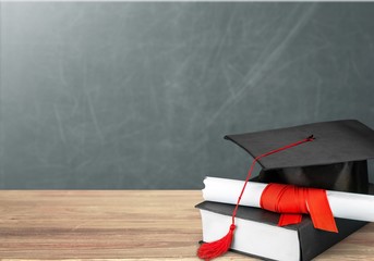 Graduation mortarboard on book on  background