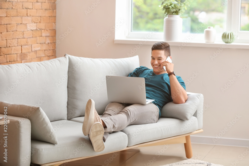 Young freelancer talking by phone while working on laptop at home Young freelancer talking by phone while working on laptop at home
