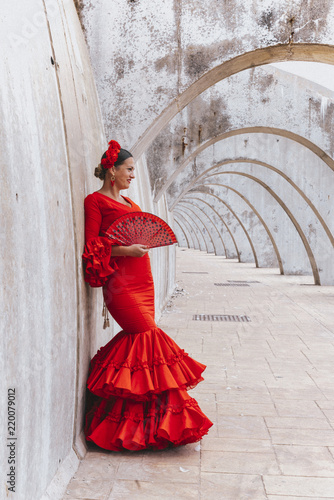 Woman dressed in red dancing flamenco with red fan