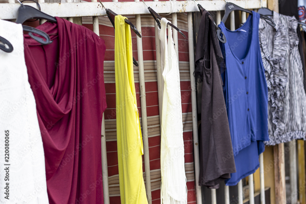 Colorful dresses hanged on metal bars that are ready to be sold near street