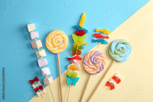 Delicious lollipops and candies on color background