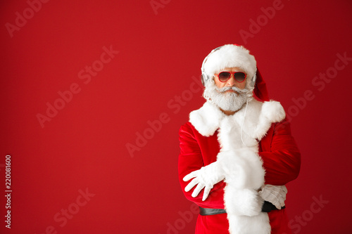 Portrait of cool Santa Claus listening to music on color background