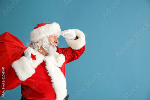 Santa Claus with bag full of gifts on color background © Pixel-Shot
