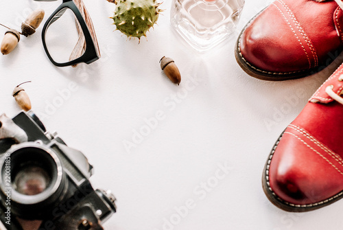 fashion leather shoes for autumn, spring. red boots on a white background lie with the camera, glasses and acorns.