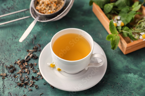 Cup of delicious camomile tea on green table