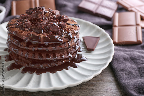 Plate with tasty chocolate pancakes on wooden table, closeup photo