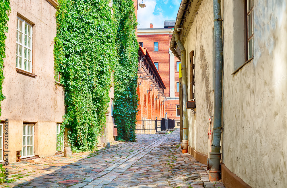 Narrow cobblestoned narrow street in Riga, Latvia during sunny day. Old Town of Riga.