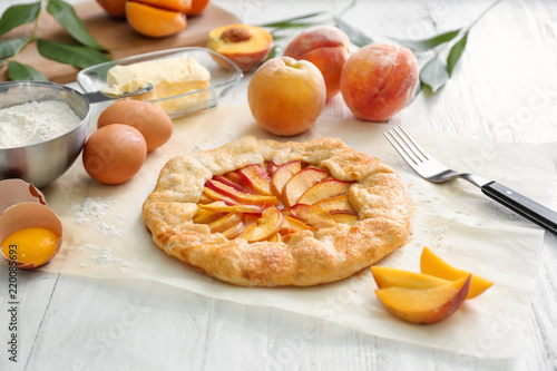 Parchment with delicious peach galette on white table photo