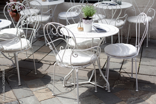 outdoor terrace of cafe with beautiful white wrought iron chairs and table in sunny summer day. photo