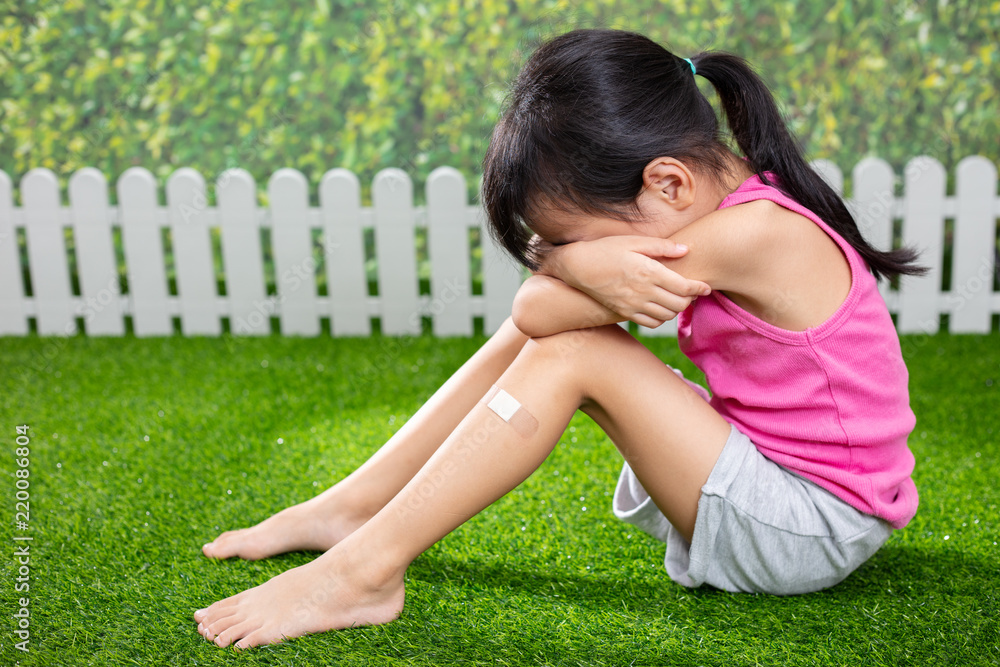 Asian Little Chinese girl sitting on the grass and crying Asian Little Chinese girl sitting on the grass and crying