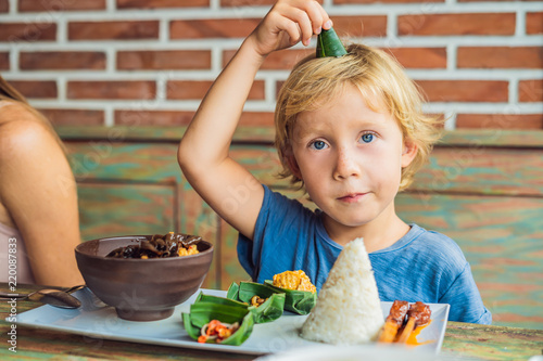 Boy eats in a cafe. Lifestyle. A dish consisting of rice, fried fish with wood mushrooms and different kinds of sauces photo