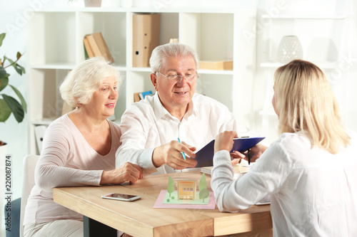 Mature man signing a mortgage loan agreement in office of real estate agent