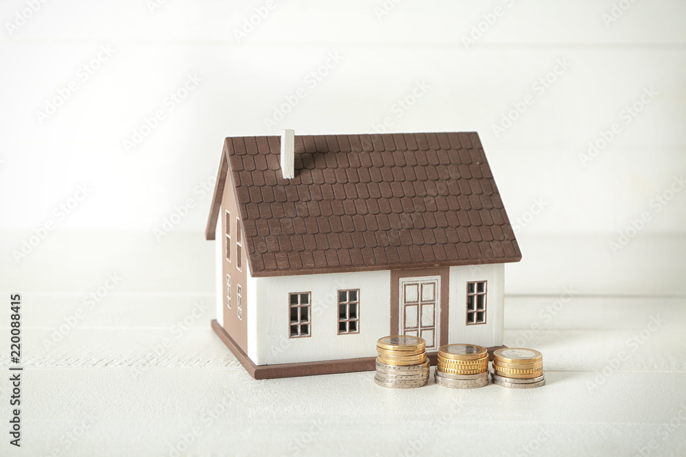 House model and coins on white table. Mortgage concept House model and coins on white table. Mortgage concept
