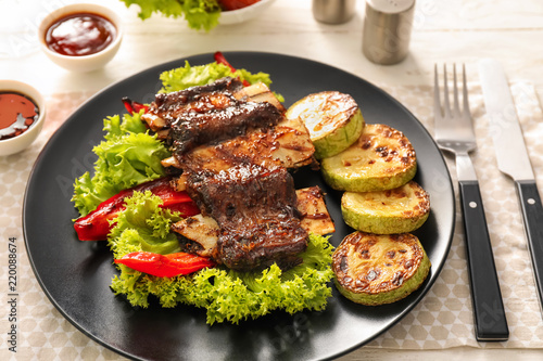 Delicious grilled ribs with vegetables on plate
