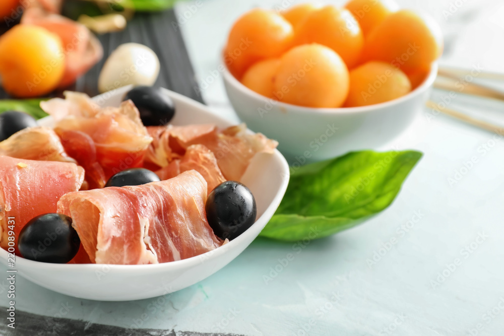 Bowl with prosciutto and olives on light table Bowl with prosciutto and olives on light table