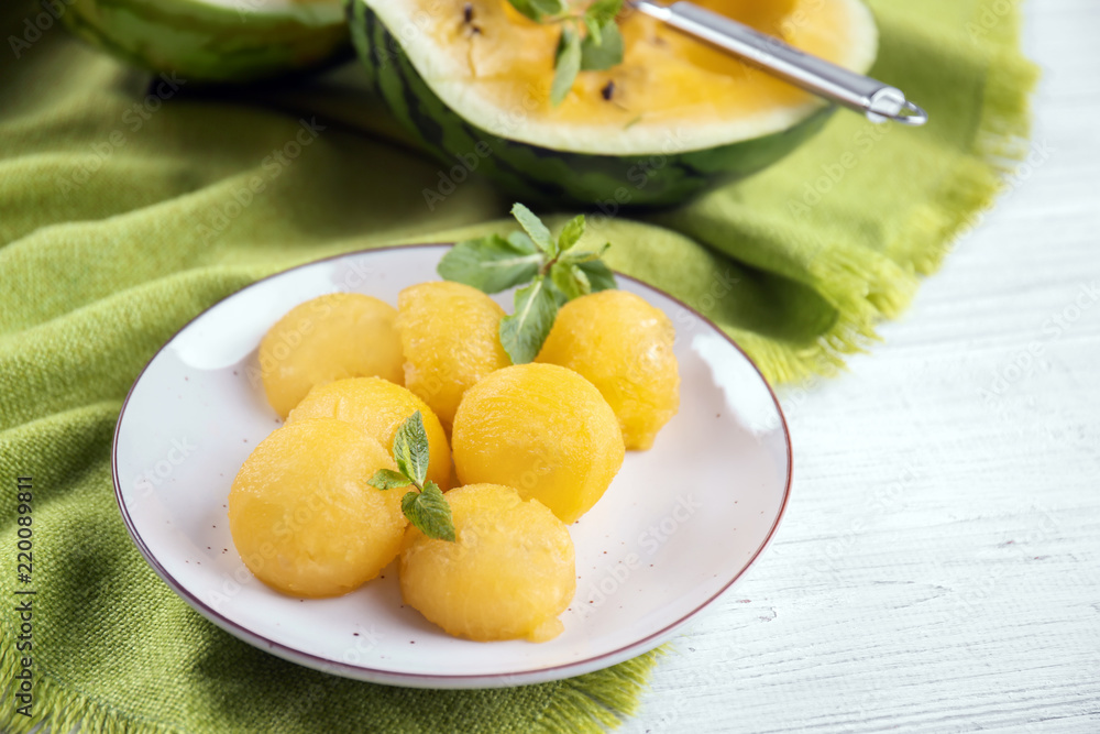 Plate with yellow watermelon balls on table