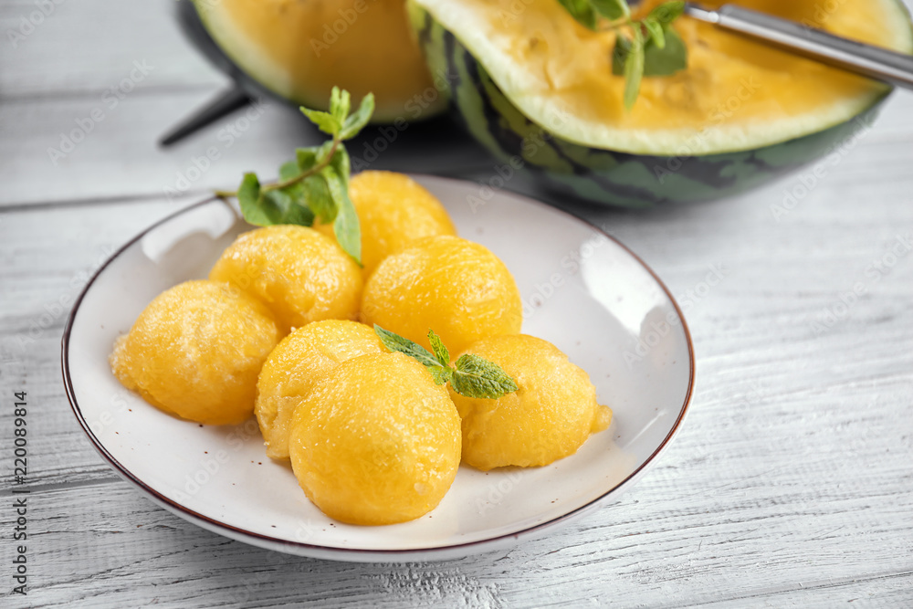 Plate with yellow watermelon balls on light table Plate with yellow watermelon balls on light table