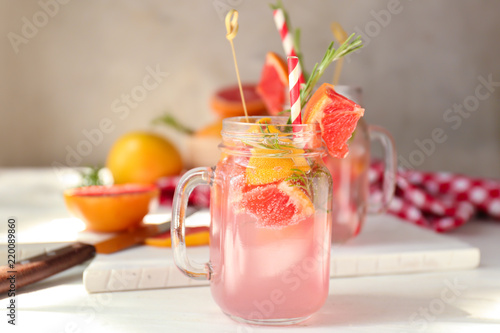Fresh grapefruit cocktail with rosemary in mason jar on light table