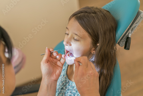 Little girl at the reception in the dentist's office. little girl sitting in a chair near a dentist after dental treatment. Little girl sitts in the dentist's office
