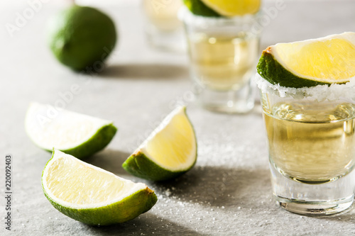 Mexican Gold tequila with lime and salt on gray background