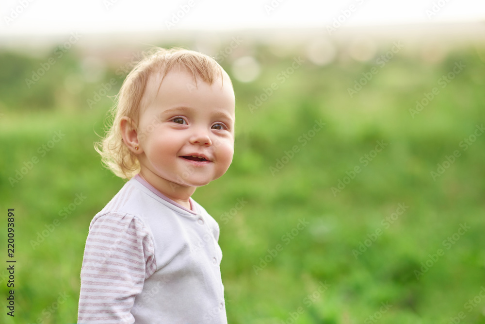Smiling little girl walking on green field.