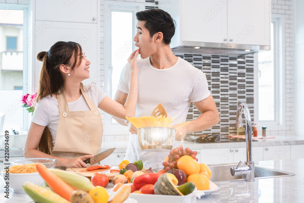 Asian couples feeding food together in kitchen. People and lifestyles concept. Sweet honeymoon and Holidays concept. Valentines day and wedding theme. Puppy love and romantic theme.