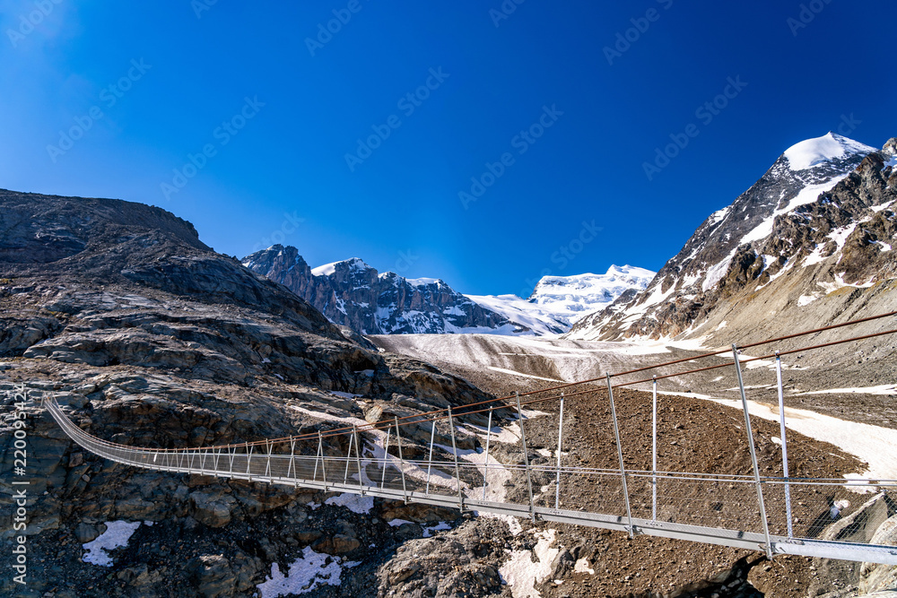 Obraz premium Scenic veiw of hanging bridge over the Glacier de Corbassiere on a mountain trail around Valais Swiss Alps.