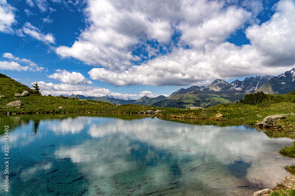 Obraz premium Scenic view of beautiful landscape in Swiss Alps. Fresh green meadows and snow-capped mountain tops with mountain lake in a front in springtime, Switzerland.
