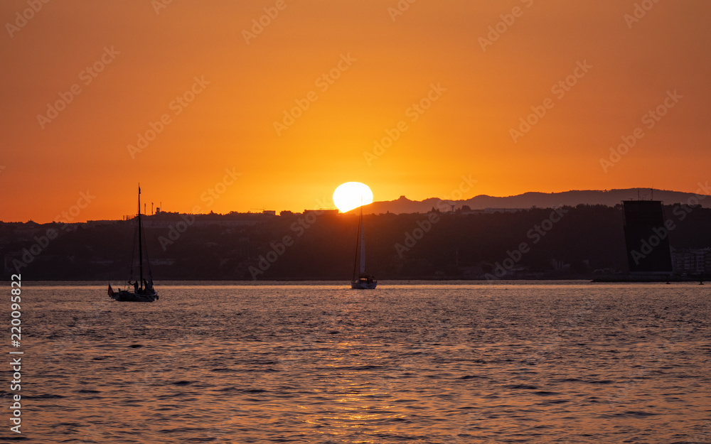 Sunset over the Tagus River; Lisbon, Portugal. A tranquil view of the sun setting with a foreground yacht taking in the view.