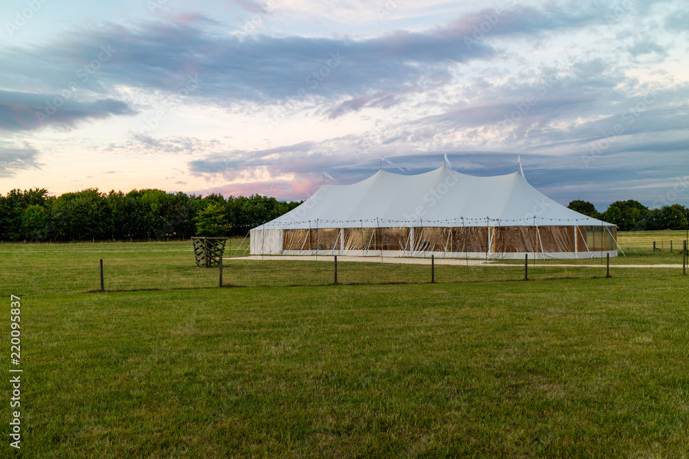 A marquee set up in a field in the evening