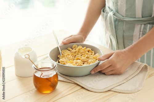 Woman holding bowl with corn flakes at table