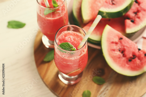 Glasses with fresh smoothie and watermelon slices on wooden board