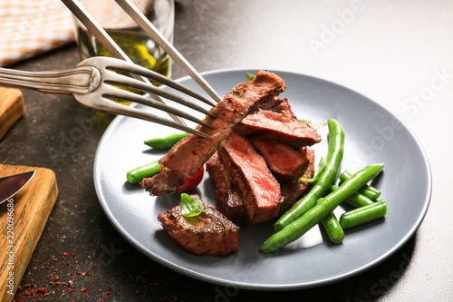 Eating of tasty grilled steak with green beans, closeup