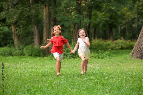 Cute little girls running in park on summer day