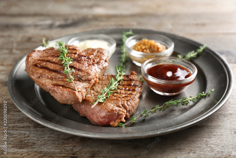 Tasty grilled steak with different sauces on metal tray