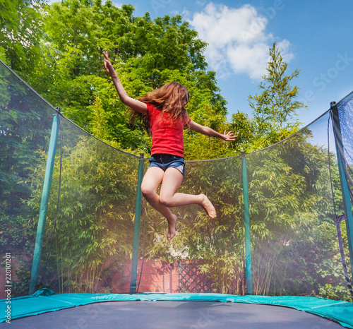 Active girl jumping on trampoline outdoors