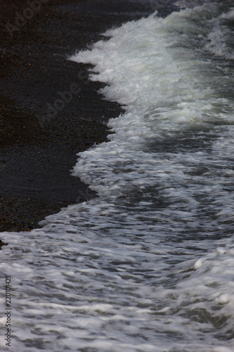 The surf wave line on a dark pebble beach in the evening
