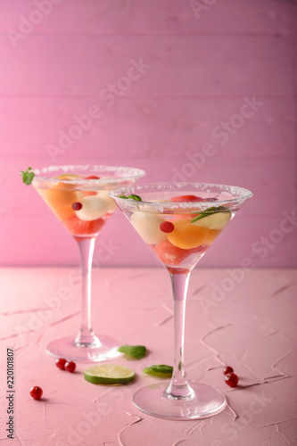Glasses of delicious cocktails with melon balls on color table