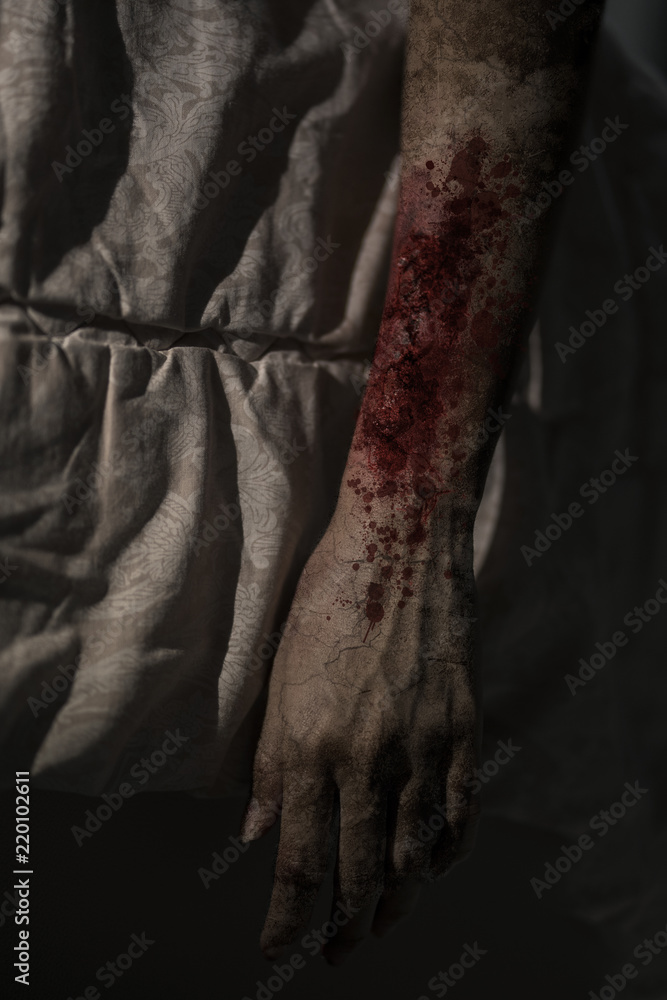 Hand of zombie woman with a bloody wound