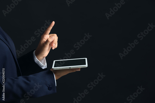 Businesswoman with tablet PC using virtual screen on dark background