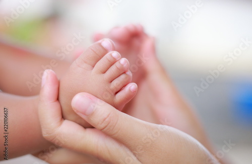 The baby's foot in the embrace of mother's hands.