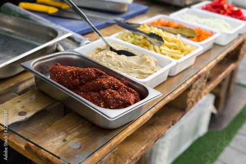 products for cooking falafel in dishes on a wooden table. Street food ready to serve on a food stall.