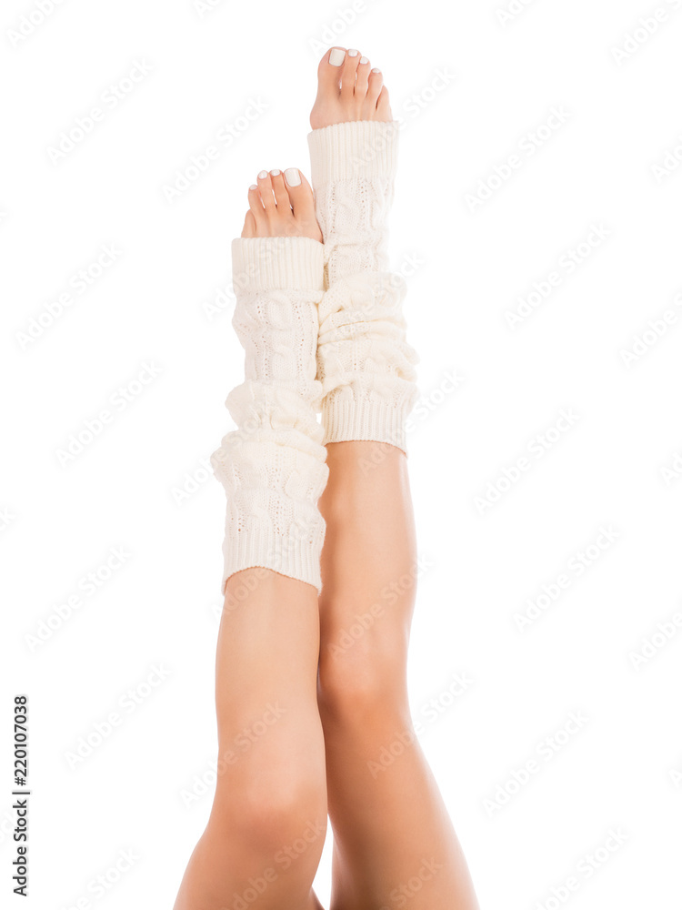 Female slim legs in white leg warmers. White pedicure. Close up