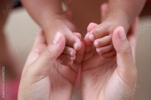 The baby's foot in the embrace of mother's hands. © MRSOMPHOT
