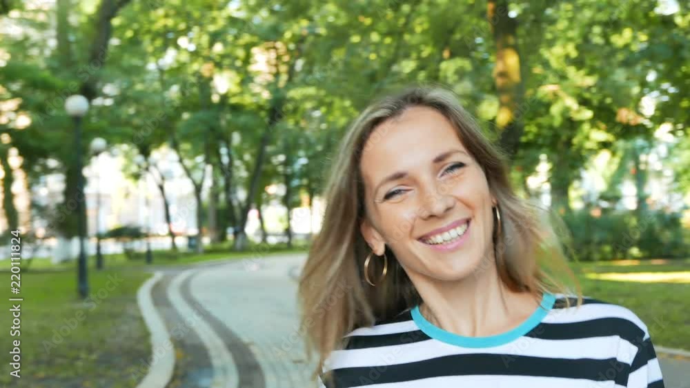           4k.Pretty slender woman smile in  summer  city park. Steady shot