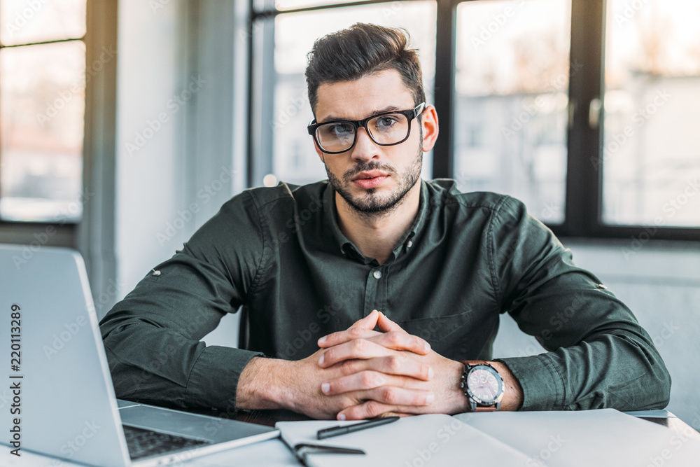businessman sitting at table in office and looking at camera businessman sitting at table in office and looking at camera