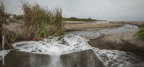 Water spilling inside Lluta river wetlands, water contamination inside the beach close to the sea. Arica, Chile photo