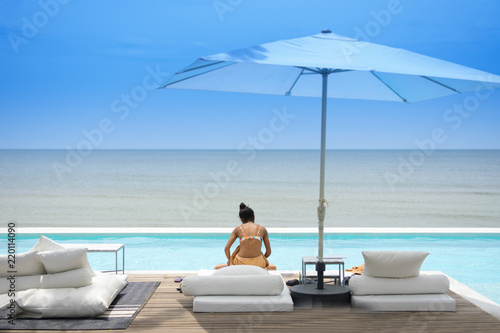 Woman tourist is taken vacation holiday and sitting at the pool on beach side in Thailand.