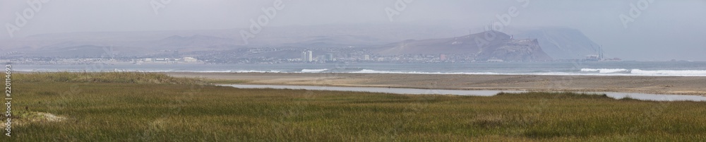 Arica city skyline from Lluta river wetlands with the Pacific Ocean crashing the beach and the typical view of 