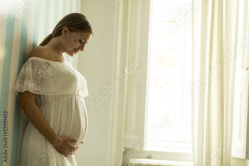 Young pregnant woman standing by the wall Free Download Young pregnant woman standing by the wall - GFXLoad